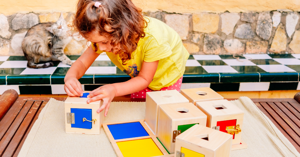 menina concentrada brincando com blocos educativos Montessori coloridos ao ar livre