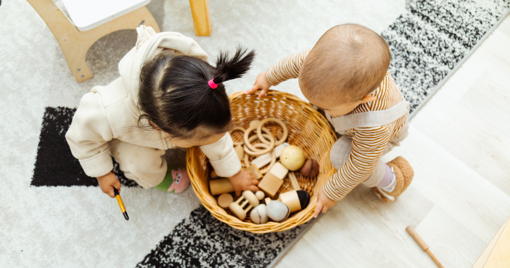 bebês explorando brinquedos sensoriais Montessori em uma cesta de vime no chão